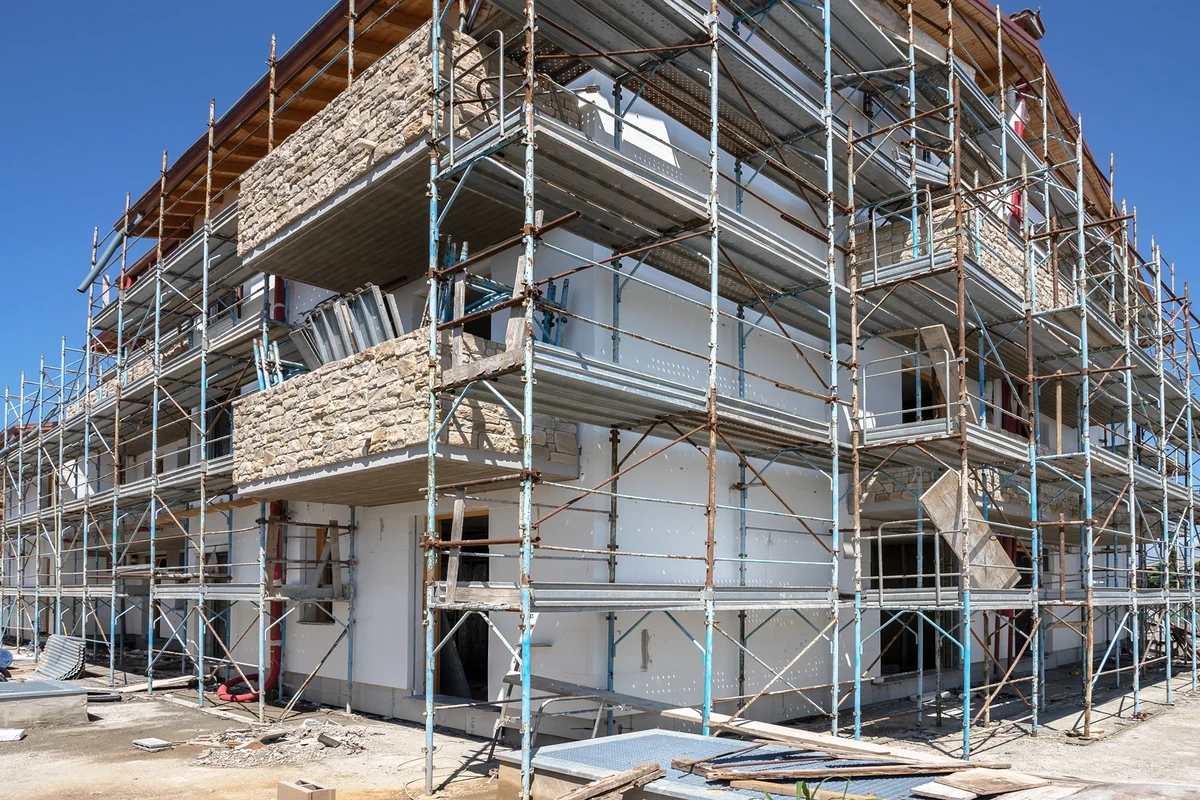 Mehrstöckiges Wohngebäude mit Stahlgerüst bei Fassadensanierung und Putzarbeiten an Außenwänden