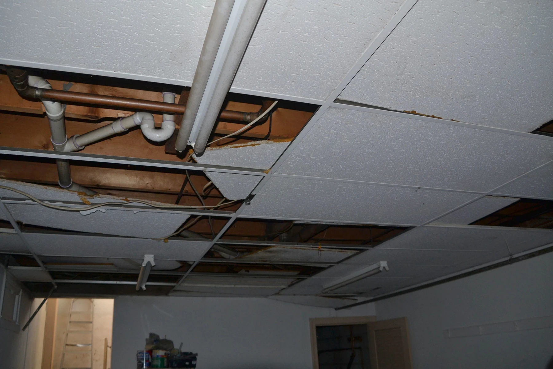 Decke mit fehlenden Abhangdeckenplatten und freigelegten Leitungen zur Wasserschaden Sanierung