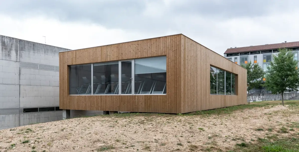 Moderner, holzverkleideter Flachbau mit großen Fensterfronten an Hanglage, Beispiel für Fassadensanierung