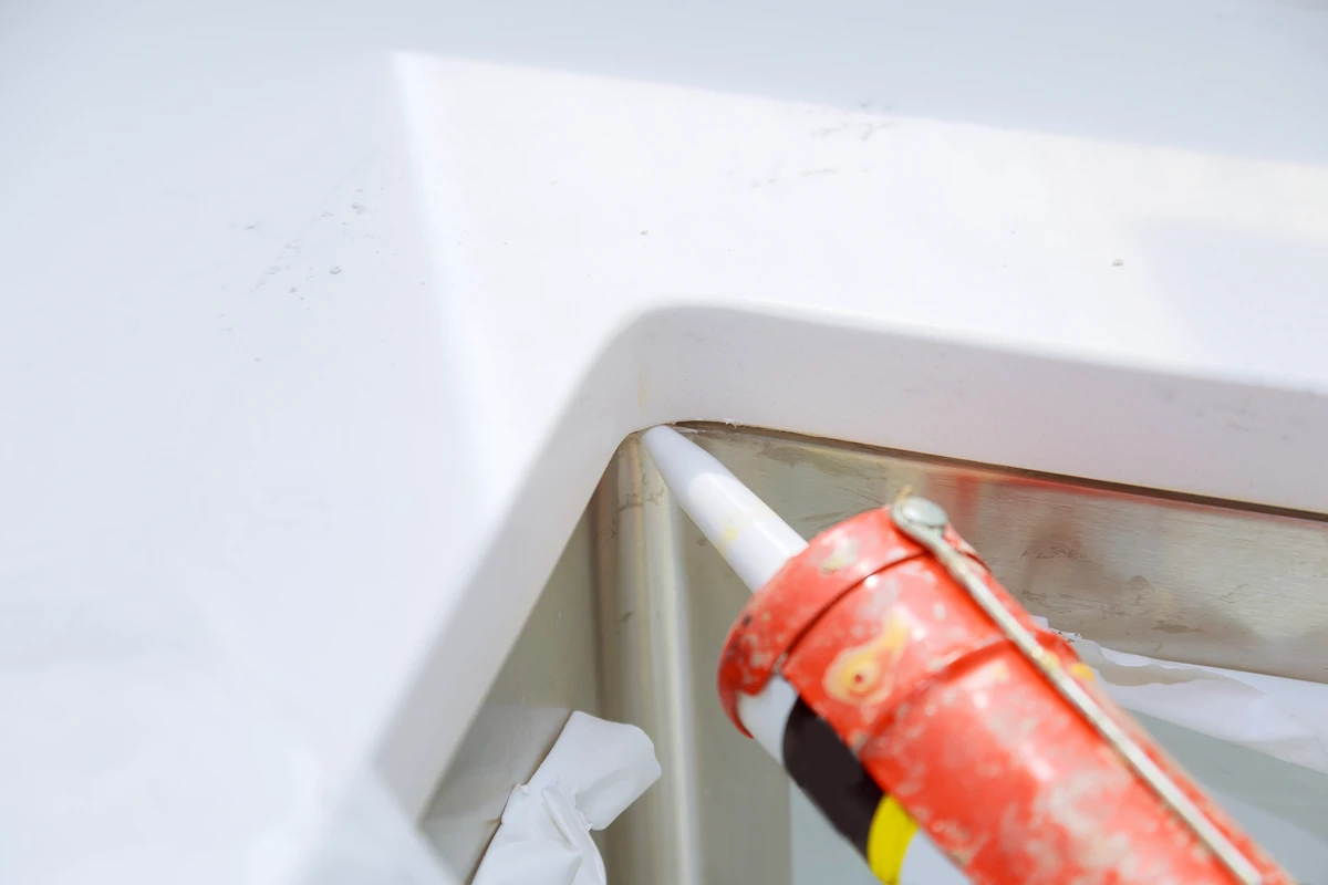 Abdichtung der Eckfuge zwischen Waschtischplatte und Edelstahlspüle mit Sanitärsilikon
